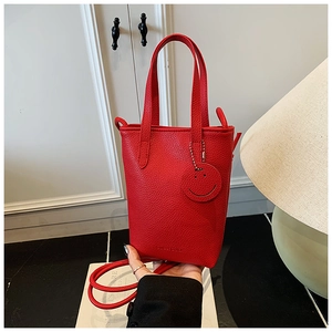 Detail of red pebbled leather mini tote bag with smile charm and adjustable strap