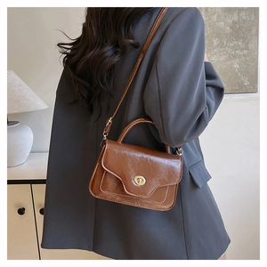 Close-up of vintage brown saddle bag with shiny finish and golden round twist lock detail