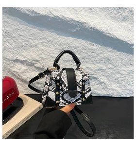 Close-up of snake skin pattern handbag with golden studs and black curved handle
