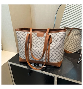 Detail view of vintage tote bag with monogram pattern and brown leather straps on a shelf