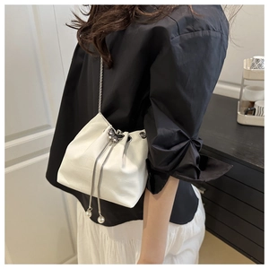 Close-up of white crocodile pattern bucket bag with silver butterfly lock and pearl charms