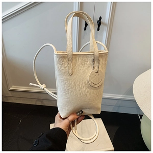 Detail of creamy white pebble leather handbag with knot strap and smiley charm
