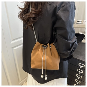 Détail du sac seau marron effet crocodile avec chaîne argentée et perle papillon