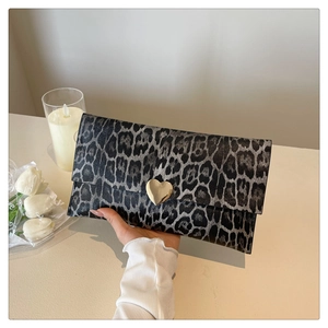 Détail de pochette enveloppe léopard avec boucle métallique dorée en forme de cœur