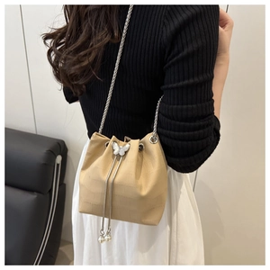 Detail of beige bucket bag with crocodile texture, silver butterfly and pearl drawstring
