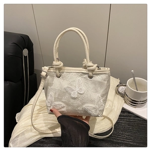 Detailed macro view of white lace fabric and 3D butterfly appliques on a sweet crossbody bag