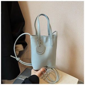 Detail of light blue pebble leather handbag with silver smiley face charm and strap