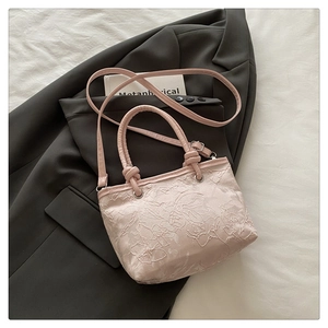 Detailed view of pink floral lace embroidery and knot handle on a small handbag