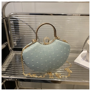 Detail of light blue heart-shaped denim evening bag with pearls and diamond handle