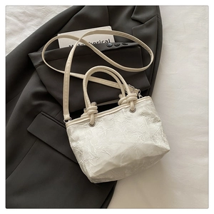Macro detail of white floral lace fabric and delicate embroidery on this tote bag