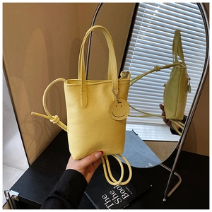 Detail of yellow lychee leather mini tote with smile charm and mirror reflection