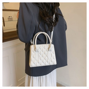 Detailed back view of a white quilted crossbody bag with adjustable strap and metal feet