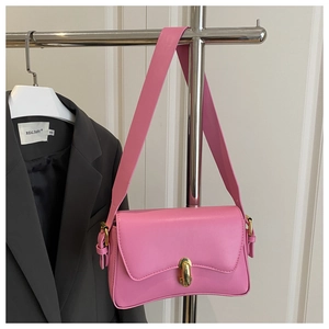 Detailed close-up of a pink matte leather underarm bag with gold capsule metal buckle