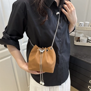 Sac seau marron à motif crocodile avec breloque papillon argentée et perles