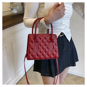 Detail of red quilted PU leather handbag with elegant top handle and crossbody strap