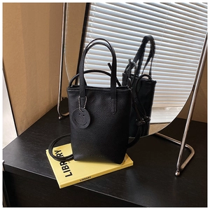 Detailed texture of black lychee grain leather tote bag with smiley face charm
