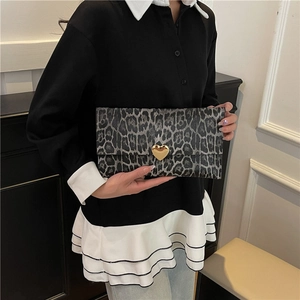 Pochette léopard avec fermoir cœur doré tenue à la main pour un look chic