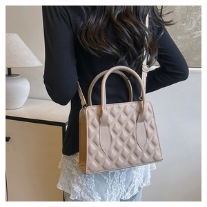 Fashionable beige quilted crossbody bag with top handles shown on model back view