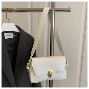 Detail of off-white PU leather shoulder bag with gold metal clasp and wide strap