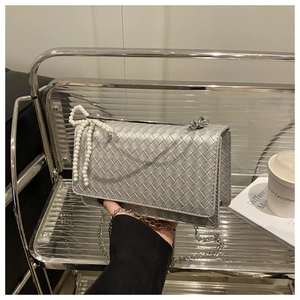 Detail of silver woven texture flap bag with pearl bow charm and chain strap