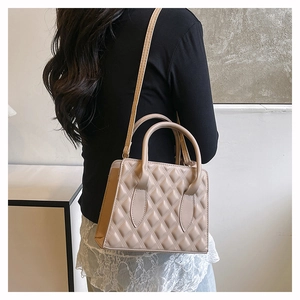 Quilted beige crossbody bag with diamond stitch detail shown on model for size scale