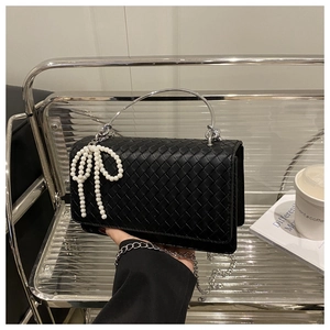 Detailed view of black woven faux leather texture with silver metal handle and pearl charm