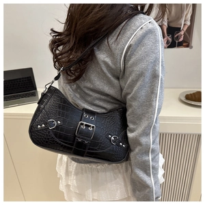 Side view of black croc-effect baguette bag with silver buckle worn by a model