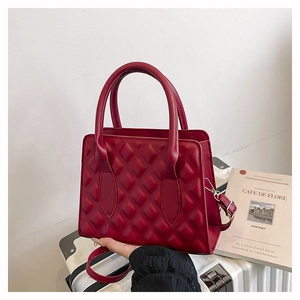 Detail of red quilted leather handbag with round handle and silver metal hardware
