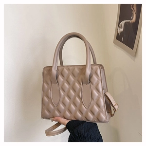 Detail of beige quilted leather handbag with top handles and detachable shoulder strap
