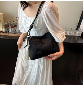Détail de la broderie papillon et du gland vert sur le sac fourre-tout noir
