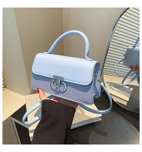 Detail of light blue crossbody bag featuring woven texture and silver double-ring lock