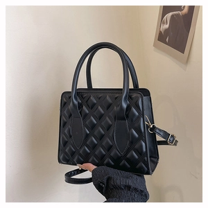 Close-up of black quilted crossbody bag with golden hardware and adjustable strap