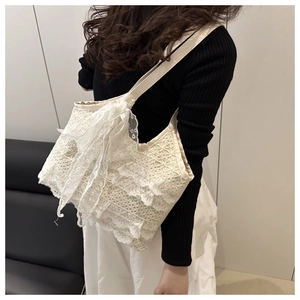 Detail of white lace beach tote bag featuring tiered ruffles and a large decorative bow