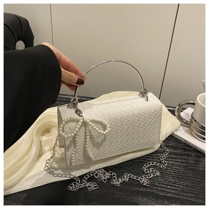 Detail of white woven texture handbag with silver metal handle and pearl bow charm