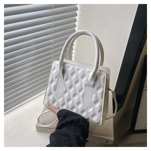Close-up of white quilted PU leather handbag with elegant top handle and crossbody strap