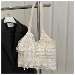 Detailed close-up of white lace tote bag with tiered ruffles and large ribbon bow detail