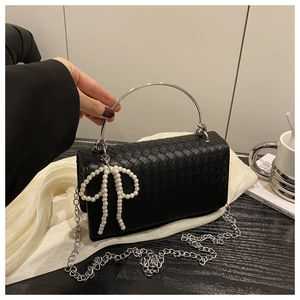 Detail of black woven leather texture with silver metal handle and pearl bow charm