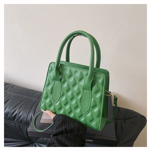 Detailed view of the green quilted leather texture and golden metal buckle on the handbag