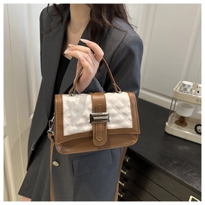 Détail du sac bicolore avec matelassage cœur et fermoir rotatif sur costume gris