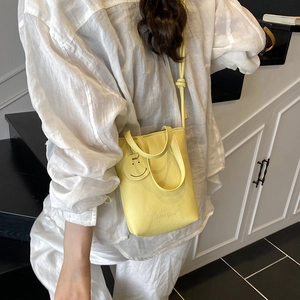 Chic yellow litchi pattern handbag with cross-body strap and smiley face pendant charm