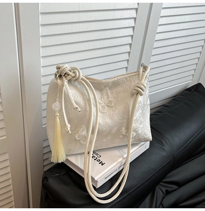 Détail du sac cabas en dentelle brodée avec papillons 3D et pompon jaune élégant