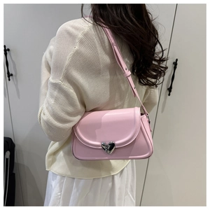 Vue détaillée du sac à bandoulière rose en cuir avec boucle cœur sur un modèle