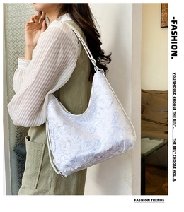 Détail d'un sac à bandoulière blanc à paillettes et pétales 3D sur un mannequin