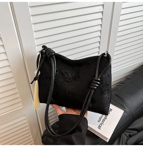 Gros plan du sac fourre-tout brodé noir avec détails de pompons jaunes décoratifs