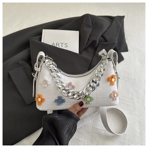 Detail of white crocodile pattern shoulder bag with colorful plush flowers and silver chain