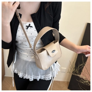 Détail du sac à main beige élégant avec logo en métal et poignée ronde large