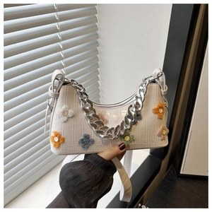 Detail of white crocodile pattern shoulder bag with colorful plush flower charms and silver chain