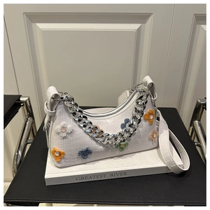 Detailed macro of white crocodile pattern shoulder bag with colorful felt flowers and silver chain