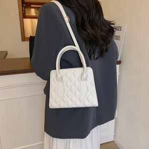 Minimalist white quilted small square bag with top handle and adjustable shoulder strap