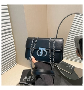 Detail einer schwarzen Lackledertasche mit silberner T-Schnalle und elegantem Kettenriemen